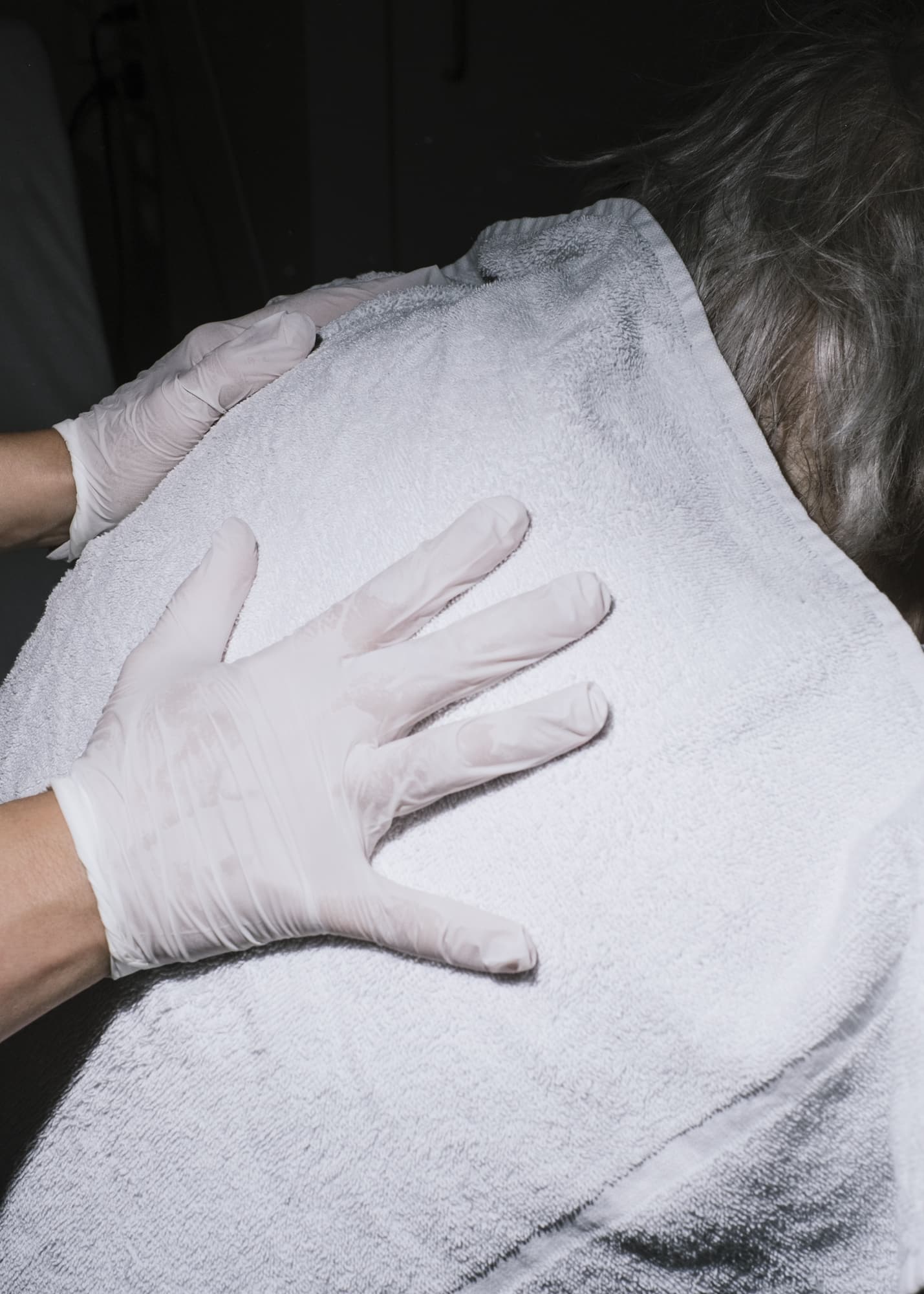 Nicht muede werden —  Hand detail of a nurse wiping sweat off a patient's back with a towel